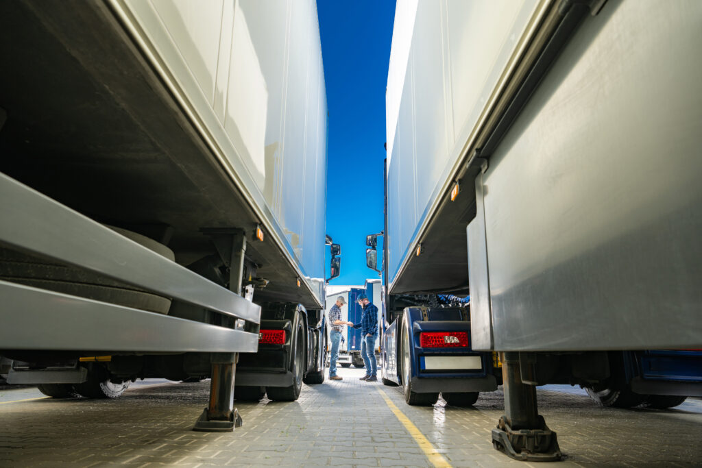 Vue entre deux remorques de camions avec des chauffeurs discutant dans une zone logistique à Nantes.