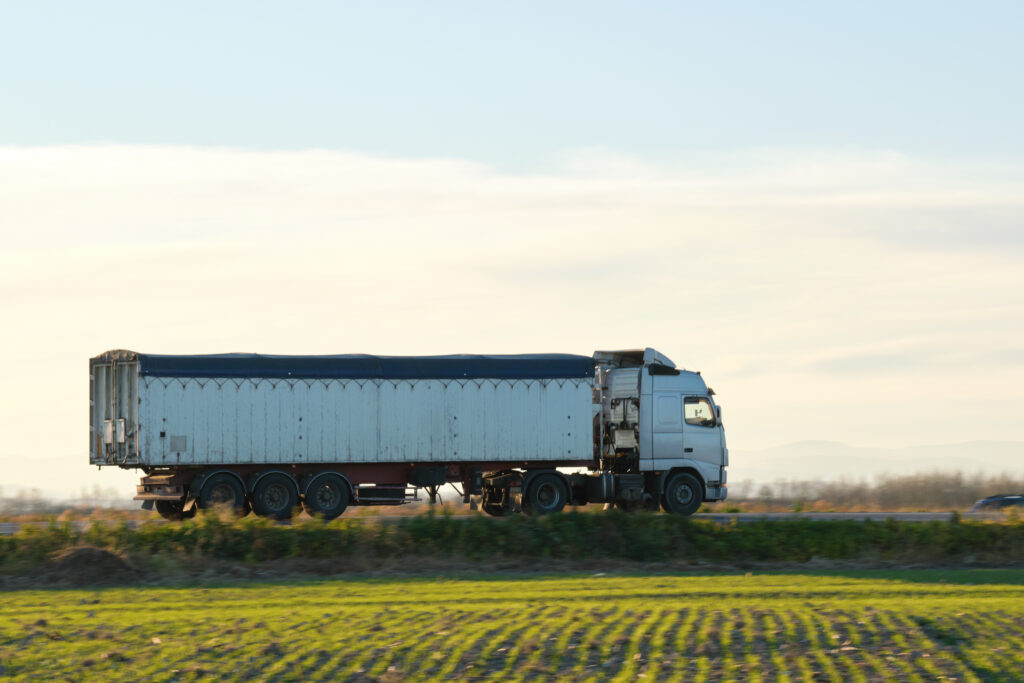 Camion avec remorque bâchée roulant sur une route en campagne près de Nantes.