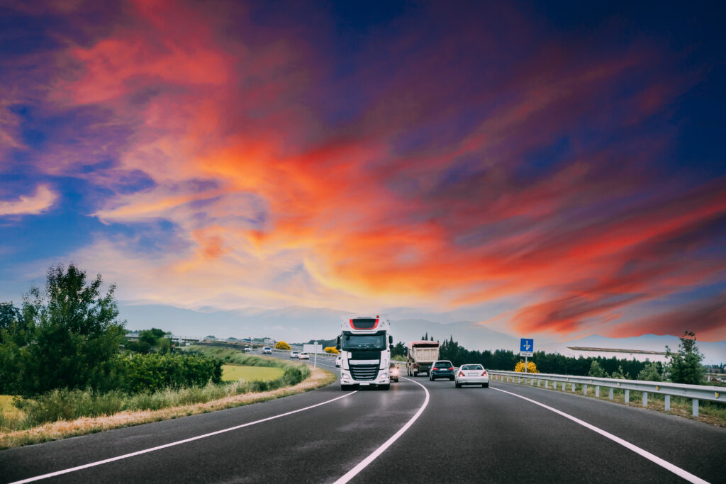 Camion blanc roulant sur une autoroute au coucher de soleil, transport routier à Nantes.